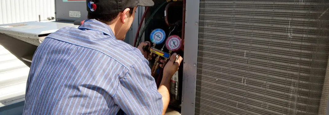 HVAC technician servicing a condenser unit in Valinda