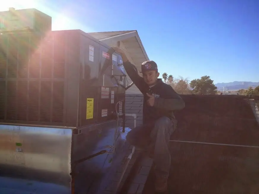 HVAC technician performing AC Tune-Up on a rooftop unit in Valinda